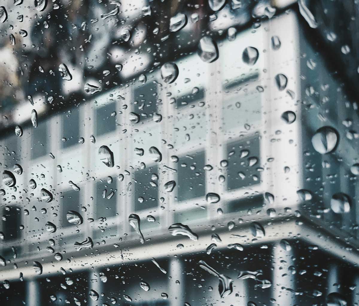 Regen auf Fenster dahinter Wohnungen